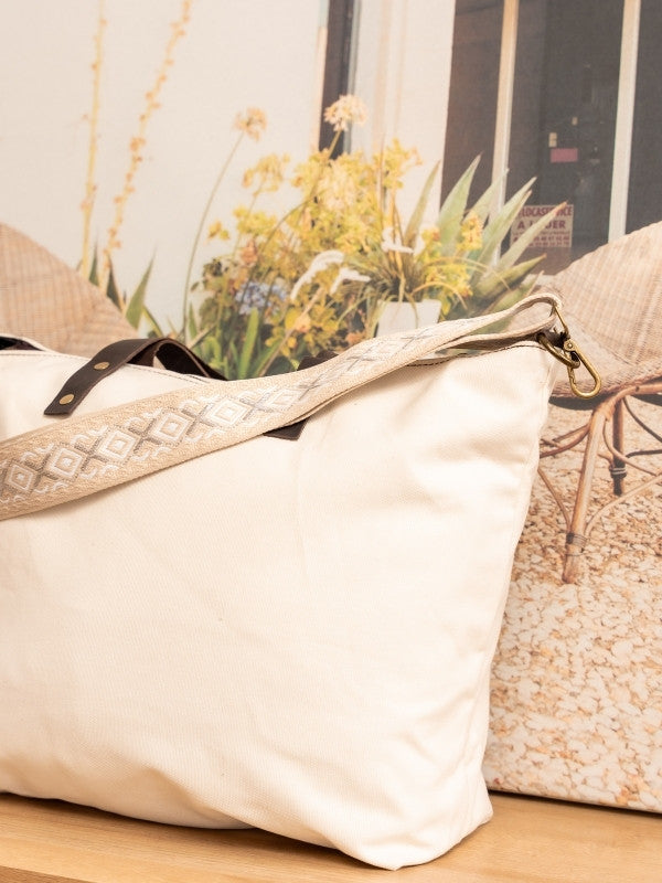 Bolso de loneta color blanco crudo con correa.