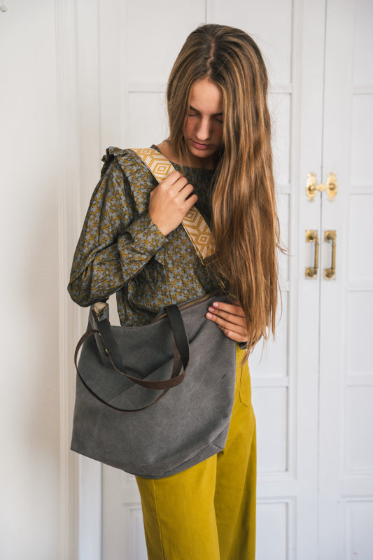 Bolso shopper de color gris antracita colgado del hombro con asa estampada y combinado con blusa estampada y pantalones