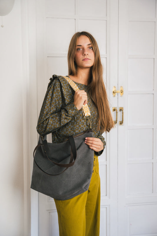 Bolso shopper de color gris antracita colgado del hombro con asa estampada y combinado con blusa estampada y pantalones