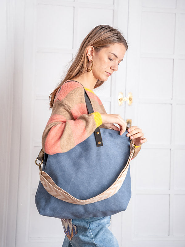 Bolso shopper de color azul lavado con asa estampada combinado con jersey de rayas marrón y rojo con puños amarillos